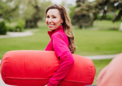 Darla walks with a red yoga bolster under her arm.