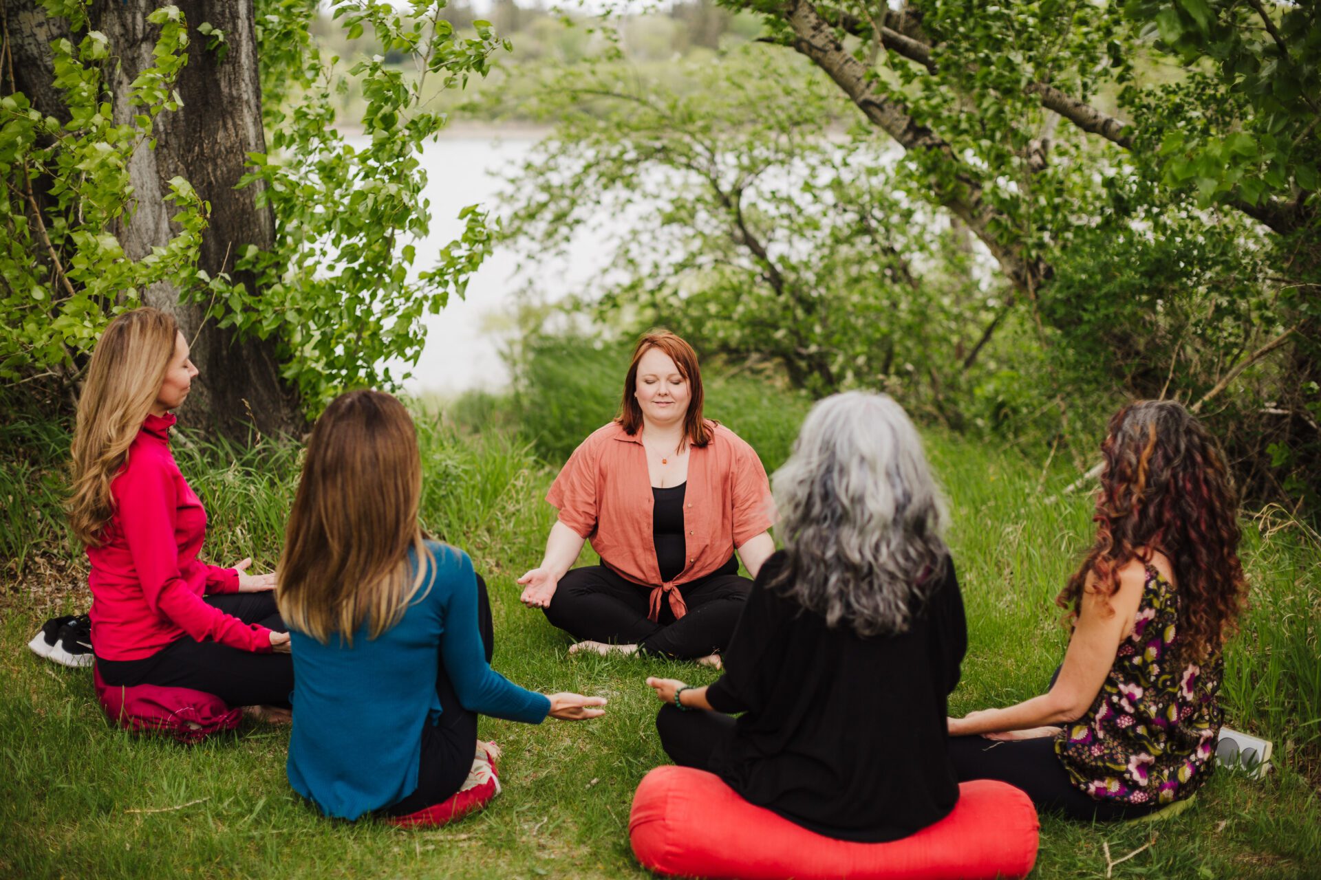A group of women sit outside, meditating.